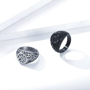 Detailed macro view of silver and black Viking Vegvisir compass rings with rock texture