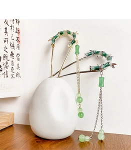 Close-up of bamboo-style hairpins with jade-textured finish and long metallic tassels