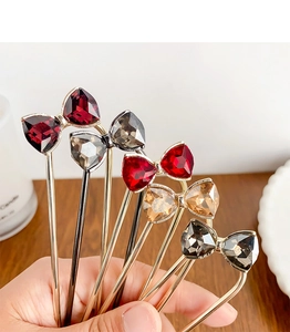 Detail view of five crystal bow hair pins in multiple colors with luxury metal plating