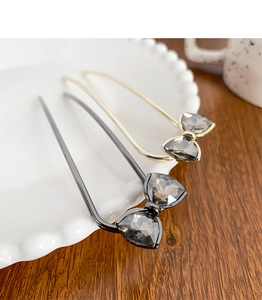 Detail of elegant U-shaped hairpins with grey crystal butterfly knots and metallic finish