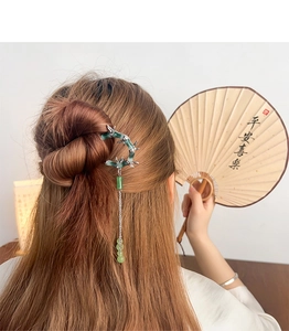 Detail of bamboo joint hair stick with tassel worn in a bun with traditional fan
