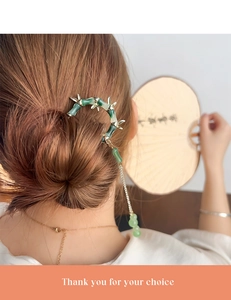 Close-up of elegant bamboo-style hair pin with green glaze and golden tassels for buns