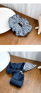 Detail of blue striped scrunchie and bow hair clip on a minimalist wooden surface
