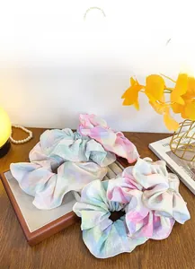 Detailed shot of three pastel gingham scrunchies in pink, mint, and yellow fabric