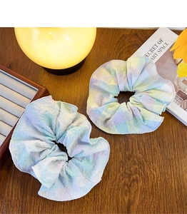 Detail of plaid pleated hair scrunchies in pastel colors on a rustic wooden background