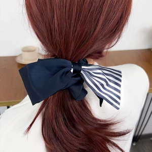 Elegant navy satin and striped fabric scrunchie worn on a low ponytail for women