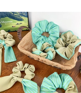 Détail d'un chouchou élégant en tissu vert forêt avec long ruban et motif à rayures