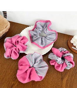Détail de quatre chouchous roses et rayés présentés sur une assiette en céramique blanche