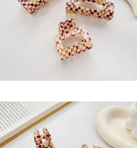 Close-up of checkerboard pattern hair claw clips in brown and beige acetate finish