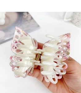 Detail of hand-held hollow butterfly hair claw clip with pink marble ink pattern texture