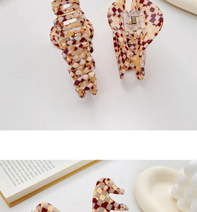 Detailed view of acetate hair claw clip with burgundy and gold checkered pattern