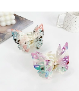 Detail of hollow butterfly hair claw with artistic ink pattern and gold metal spring