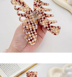 Detailed macro view of a red checkered butterfly hair claw clip with strong metal spring