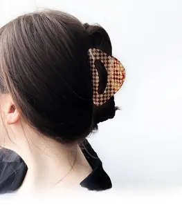 Macro view of brown checkerboard acetate hair claw clip styled on dark wavy hair