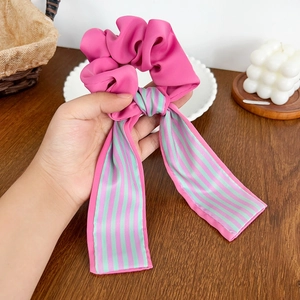 Chouchou élégant rose vif avec rubans rayés verts sur fond de bureau en bois