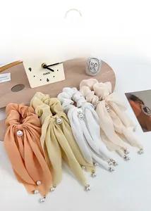 Détail de quatre chouchous en mousseline pastel avec élégantes breloques en perles