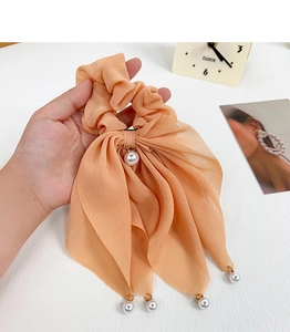 Détail du chouchou ruban pêche en tissu doux avec des perles élégantes pendues