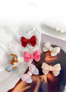 Detailed collection of assorted acetate bow hair clips on a white paper surface