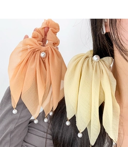 Détails de chouchous élégants avec nœuds en mousseline et perles en pêche et jaune