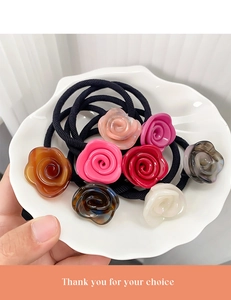 Detailaufnahme bunter Haarspangen aus Harzrosen auf einem weißen Keramikteller