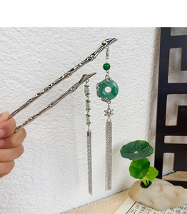 Detail of silver bamboo style hair pin with green beads and long metallic tassels