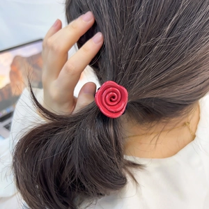 Romantisches Haargummi mit roter Acetat-Rose auf dunkelbraunem Haar, glänzendes Finish