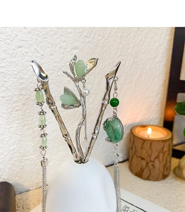 Detail of silver hairpins with green jade beads and pearls in a white ceramic vase