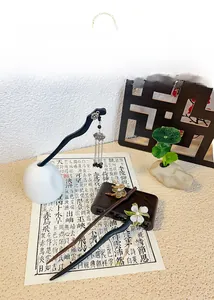 Detailed view of three Chinese style wooden hairpins with pearls and metal tassels on a desk