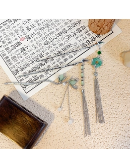 Detail of Chinese style bamboo hair stick with green jade-like ring and long silver tassel