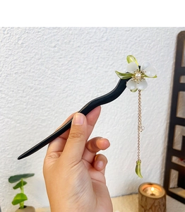 Detail of vintage wooden hair stick with elegant green leaf tassel and pearl floral design