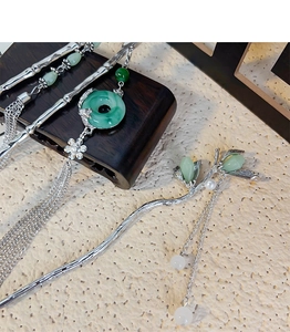 Detailed close-up of bamboo-style hairpins with green jade beads and long silver tassels