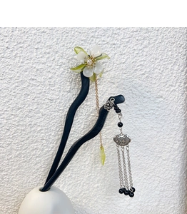 Detail of wooden hair pin with white green flower, pearl, and silver lock pendant with tassel
