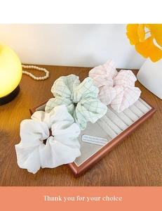 Lot de 3 chouchous en blanc, vert et rose à carreaux sur un plateau en bois