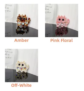Detailed view of cat-shaped acetate hair clips in amber, pink and cream white colors