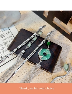 Detailed macro view of bamboo joint hair stick with faux jade tassels on wooden stand