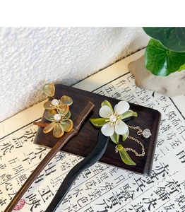 Close-up of elegant wooden hair sticks with floral details and metallic tassel accents