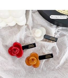 Detailed close-up of rose-shaped acetate hair clips in red, cream, and amber colors
