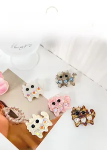 Detail of five cat-shaped acetate hair clips with heart rhinestones and bead eyes