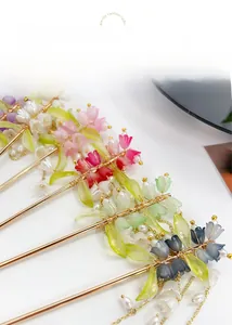 Dettaglio delle forcine a mughetto con petali colorati e nappine di perle eleganti