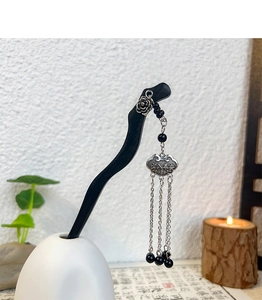 Close-up of wooden hair pin with silver tassels and flower pendant in Chinese style