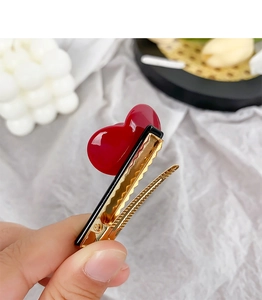Detail of a sweet red heart acetate hair clip with a gold metal duckbill base