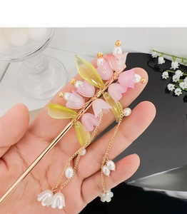 Dettaglio del fermaglio per capelli mughetto con petali rosa, perle e nappe dorate