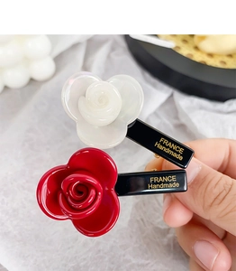 Detailed close-up of handmade acetate floral hair clips in pearl white and vivid red colors