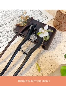 Detail of elegant wooden hair sticks with floral resin accents and long metal tassels