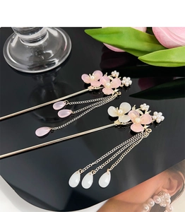 Close-up of elegant plum blossom hair pins with pink flowers and golden tassels