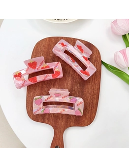 Dettaglio di fermagli per capelli rosa traslucidi con motivi fragola e pesca