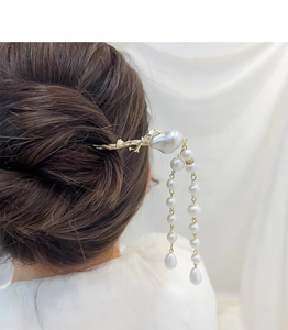 Detail of elegant plum blossom hair pin with pearls and tassels on a model's updo