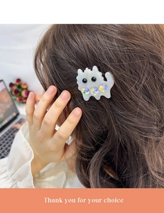 Detailed view of white acetate cat hair clip with sparkling heart rhinestones on hair