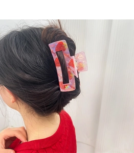 Pinza per capelli a fragola rosa traslucida mostrata in dettaglio dell'acconciatura