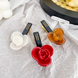 Three acetate flower hair clips in cream, red, and brown with gold metal duckbill clamps